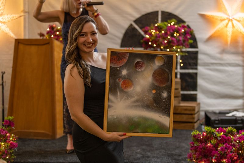 One of the evenings hosts showcasing a live auction item, a beautiful painting of a space scenescape by one of Kimberton's alumni at the Starlight Soiree as guests bid on the item