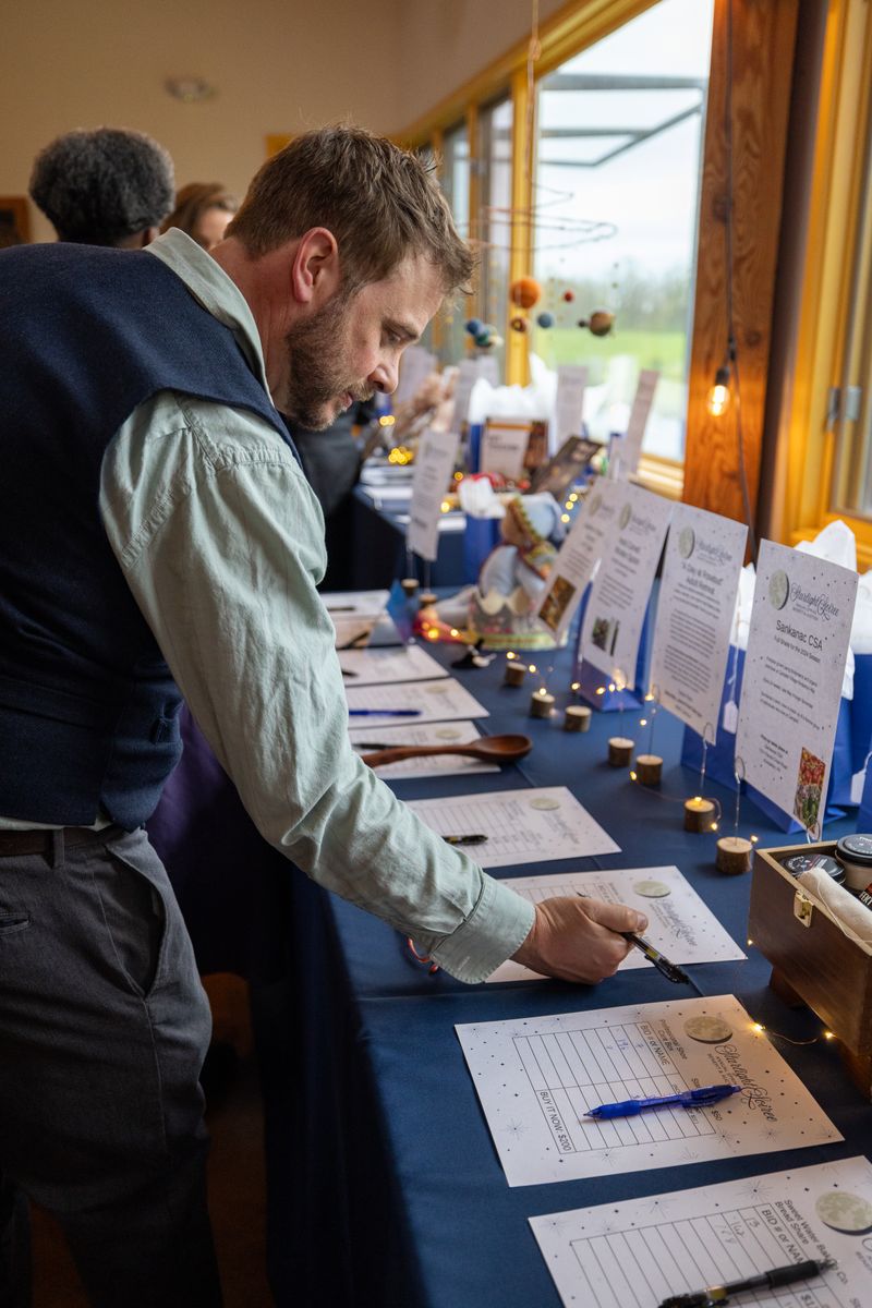An attendee considering a bid on a silent auction item at the Starlight event, surrounded by a variety of exclusive items.