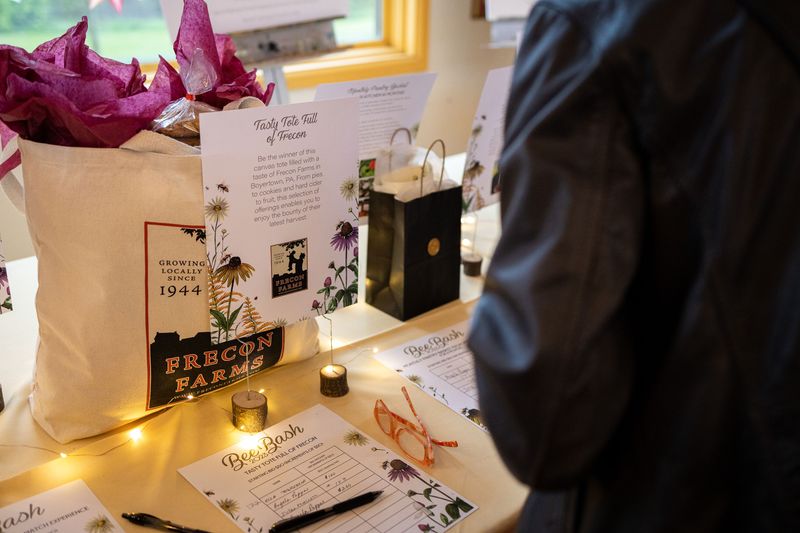 A guest at BeeBash considering a bid on the silent auction items, surrounded by a variety of exclusive items.